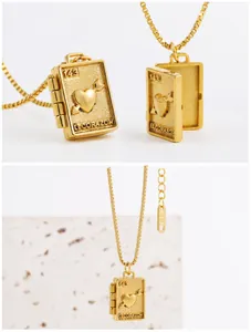 Close-up of gold book-shaped locket necklace with heart engraving and k18 tag detail
