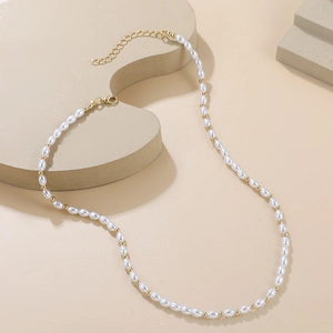 Détail d'un collier de perles avec perles dorées et fermoir mousqueton réglable