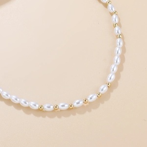 Gros plan de perles de riz blanches élégantes et de perles dorées sur un collier