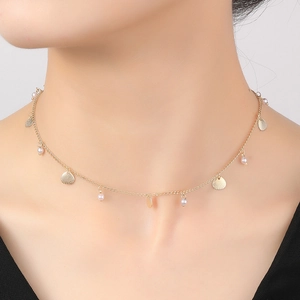 Primer plano de una gargantilla de oro de 14K con conchas finas y perlas blancas