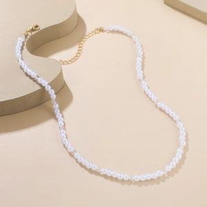 Vue détaillée de perles blanches avec fermoir mousqueton doré et chaîne d'extension