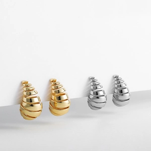 Detalle de pendientes de gota en espiral con acabados en oro de 18K y plata pulida