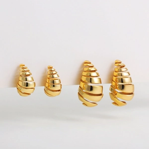 Detalle macro de pendientes de gota en espiral huecos bañados en oro de 18 quilates