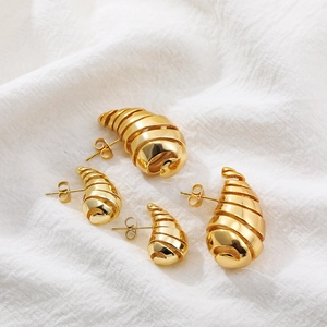Detalle de pendientes de gota en espiral hueca de oro de 18K sobre tela blanca fina
