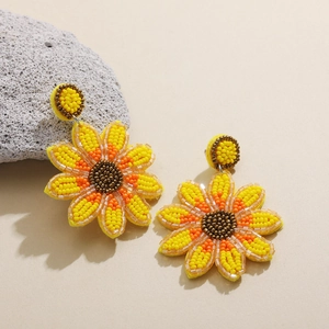 Détail de boucles d'oreilles tournesol faites main avec des perles jaunes et orange vif