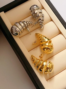 Primer plano de pendientes espirales de oro y plata en un elegante estuche de joyas