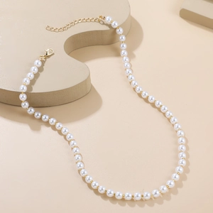 Détail de perles blanches élégantes avec fermoir mousqueton doré et chaîne d'extension
