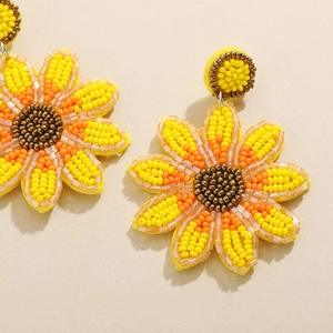 Vue macro de boucles d'oreilles bohèmes en perles en forme de tournesol faites à la main