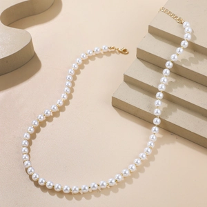 Vue détaillée d'un collier de perles blanches avec des perles dorées et un fermoir