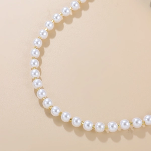 Détail macro d'un collier de perles blanches avec perles intercalaires dorées chic