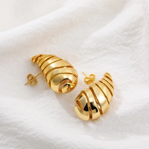 Vista macro de pendientes espirales de oro de 18K con rayas huecas y cierre de mariposa