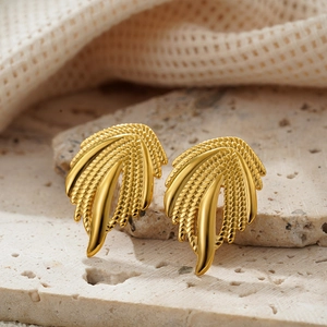 Boucles d'oreilles ailes dorées 18K texturées posées sur pierre naturelle décor