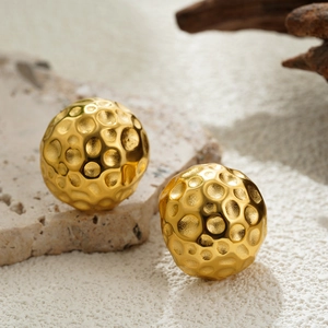 Détail de boucles d'oreilles boules dorées 18K avec texture martelée sur pierre naturelle