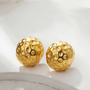 Détail macro de boucles d'oreilles boules d'or 18 carats avec texture martelée unique