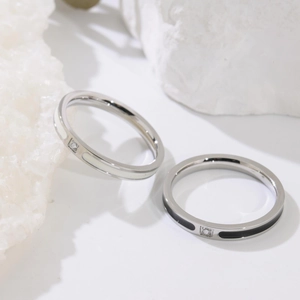 Gros plan sur des bagues en acier titane émaillé noir et blanc avec petit cristal zircon