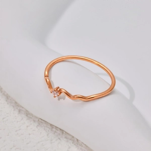 Minimalist rose gold wavy ring with a single sparkling zircon stone on a white background