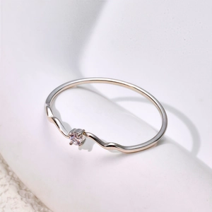 Macro detail of wave shaped silver ring featuring a small round sparkling zircon stone