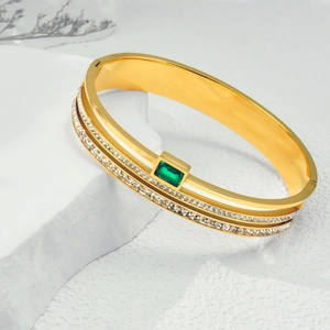 Macro detail of gold-plated bangle featuring a rectangle emerald and pavé crystals