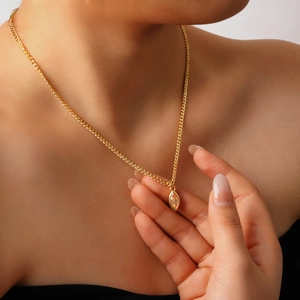 Detailed close-up of a zircon pendant necklace on a model showing golden steel texture