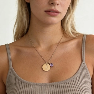 Détail du collier en titane doré avec pendentif fleur gravé et pierre de zircon violette