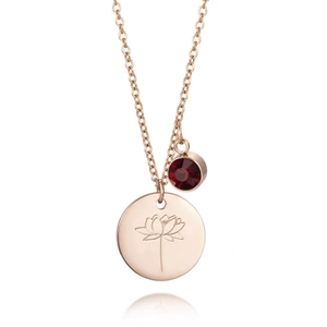 Détail du collier en titane or rose avec pendentif lotus gravé et pierre de zircon rouge