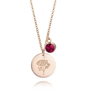 Détail du collier en or rose avec disque gravé de fleurs et pendentif en zircon rouge