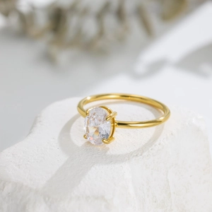 Detailed view of oval cut clear gemstone on a gold polished stainless steel ring band