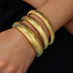 Detail van 18K vergulde gaspipe-armbanden met een hoogglanzende metaalachtige afwerking