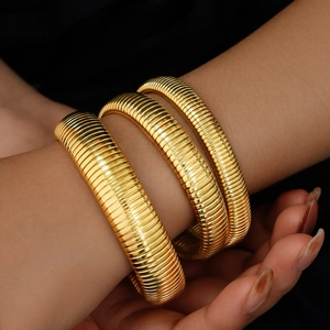 Detail van 18K vergulde flexibele Tubogas armband met metallic textuur afwerking