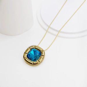 Detailed macro view of a gold necklace featuring a blue square-cut gemstone pendant