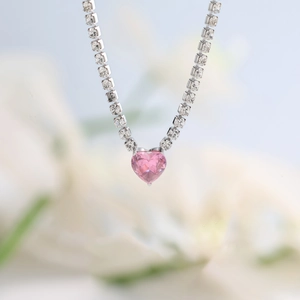 Macro shot of heart-shaped pink zircon pendant on a silver diamond-encrusted chain