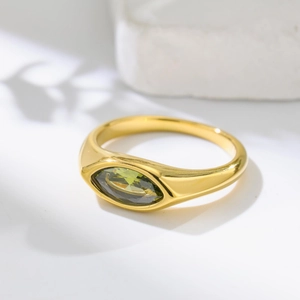 Détail macro d'une pierre marquise vert olive sur une bague épaisse plaquée or