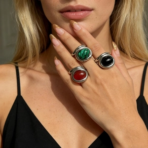 Close-up of stacked vintage silver rings featuring malachite, onyx, and carnelian stones
