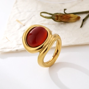 Retro wide band gold ring featuring a large oval red gemstone on textured background