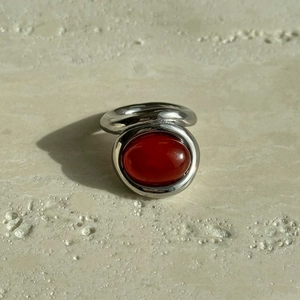 Macro detail of polished silver titanium ring with an oval reddish-brown gemstone inlay