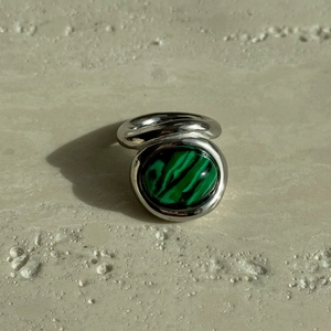 Detail view of oval green malachite stone on polished silver-tone stainless steel ring