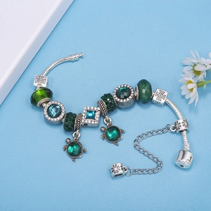 Silver bracelet featuring green cat-eye crystal turtle charms and blue glass beads