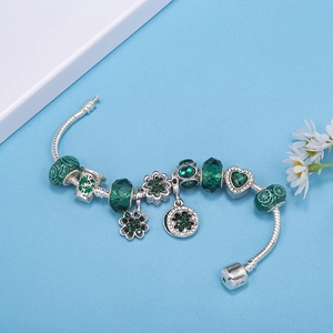 Pandora style snake chain bracelet with green crystal beads and clover charms on blue base