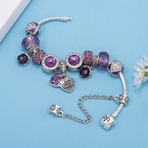 Detail of purple crystal beads and heart charm with mother engraving on silver bracelet