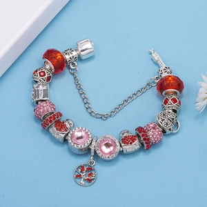 Detalle de pulsera de cuentas plateadas con dijes de corazón rojo y colgante árbol de la vida