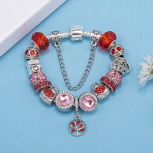 Detalle de pulsera de dijes con cuentas de vidrio rojo y colgante de la vida