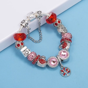 Detalle de pulsera de dijes plateada con cuentas de cristal rojo y colgante árbol de la vida