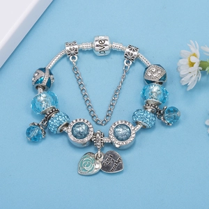 Detail of silver charm bracelet with blue glass beads and engraved heart rose pendant