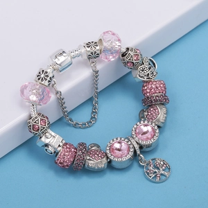 Detalle de pulsera de plata con dijes, cristales rosas y colgante de árbol de vida