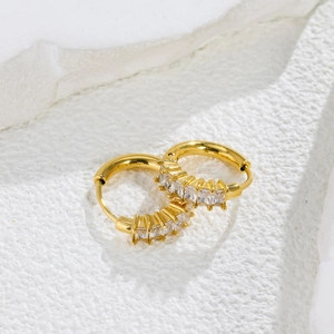Macro view of gold hoop earrings with row of clear cubic zirconia on stone background