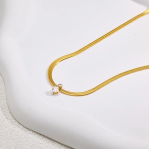 Elegante goldene Schlangenkette mit quadratischem weißem Edelstein auf modernem Hintergrund