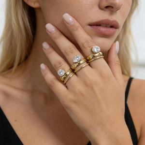 Close-up of three gold titanium rings with round and pear-shaped zircon on a model hand