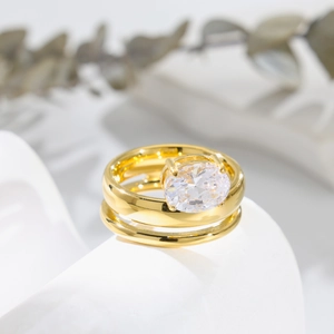Detailed close-up of a triple-layered gold zircon ring set on a white geometric platform