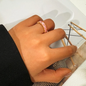 Detail shot of a gold-plated ring set with pink heart-shaped stones worn on hand