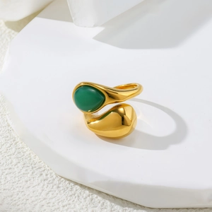 Detail of bypass ring with green gemstone and teardrop design on geometric stand